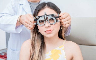 Optometrist deneme aşamasındaki hastayı muayene eden göz doktorunun elleri. Optometrist deneme çerçevesi olan genç hasta