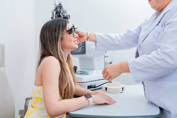 Optometrist woman examining patient with trial frame in office. Optometrist with young patient with optometrist trial frame