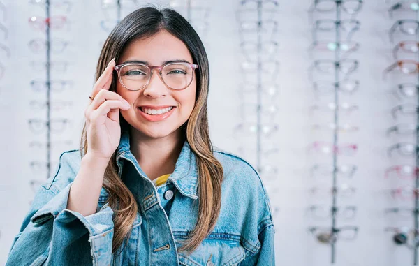 stock image Portrait of beautiful girl modeling glasses in an optical store. Happy teen girl in eyeglasses with store eyeglasses background