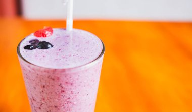 Çilekli milkshake 'in fotokopi alanı ile bulanık arkaplanını kapat. Ahşap arka planda yabanmersinli çilekli smoothie.