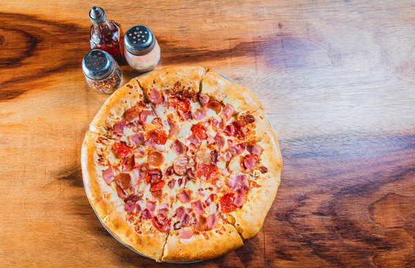 木のテーブルの上にハムとチーズピザのトップビュー 木の背景にチーズエッジのあるハムピザ — ストック写真
