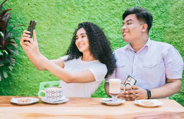 İki mutlu arkadaş kahve içip selfie çekiyorlar. Birkaç arkadaş oturup kahve içip selfie çekiyorlar.