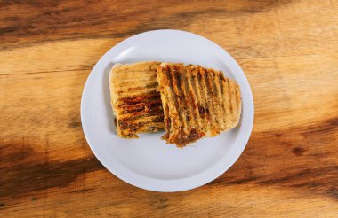 Tahta masada iki et ve tavuklu panini manzarası.