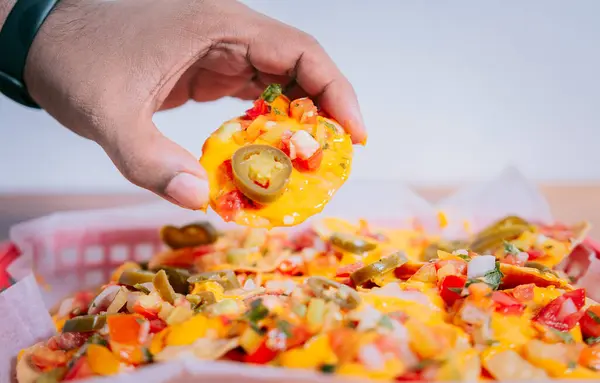 Close up of hand of taking nachos on isolated background. Hand taking and showing a nacho isolated