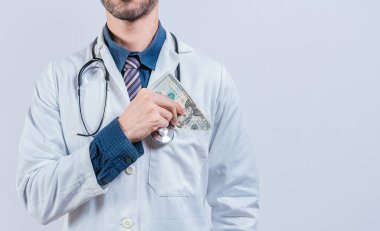 Yozlaşmış doktor, rüşvet parasını izole edilmiş bir yere koyuyor. Sahtekar doktor cebine para koydu, tıbbi rüşvet konsepti.