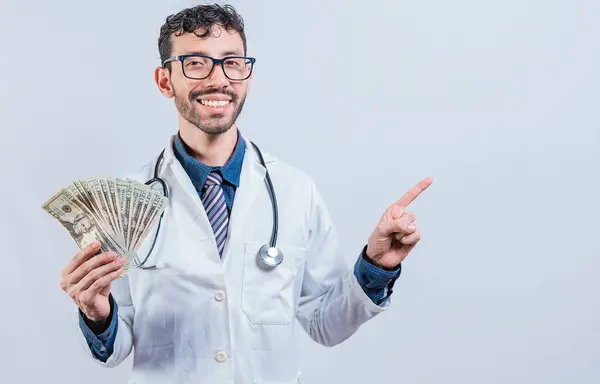 Szczęśliwy Młody Lekarz Trzymający Pieniądze Wskazujący Stronę Przystojny Uśmiechnięty Doktor — Zdjęcie stockowe