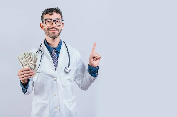 Przystojny Uśmiechnięty Doktor Pokazuje Pieniądze Wskazuje Stronę Szczęśliwy Młody Lekarz — Zdjęcie stockowe
