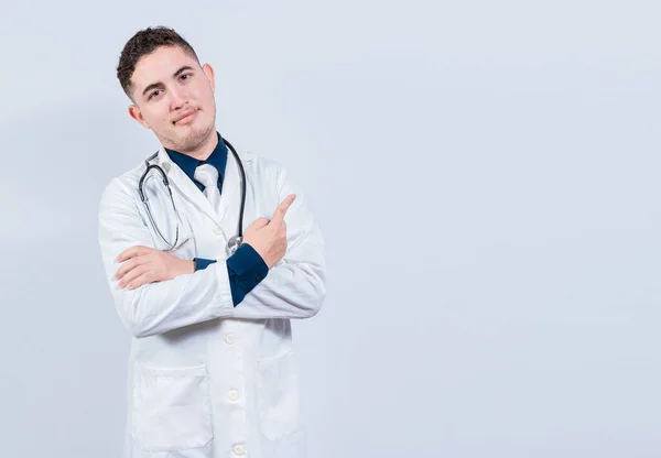 Uśmiechnięty Latynoski Lekarz Wskazujący Palcem Odizolowaną Przestrzeń Młody Lekarz Pokazuje — Zdjęcie stockowe