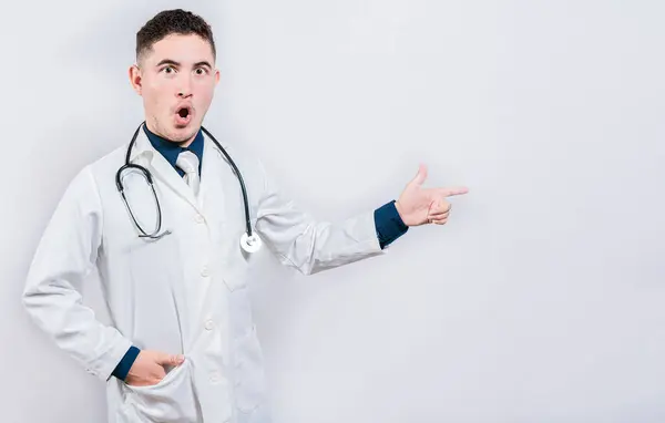 Niesamowity Lekarz Celujący Promem Kamerę Zaskoczony Młody Lekarz Wskazujący Stronę — Zdjęcie stockowe