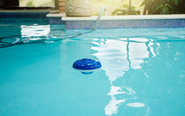 Хлор диспенсер в красивом бассейне. Хлорка плавает в бассейне. Плавучая доза для хлорирования бассейна