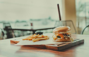 Restoran masasında servis edilen geleneksel hamburger ve patates kızartması. Tahta masada servis edilen kızarmış patatesli iştah açıcı burger.