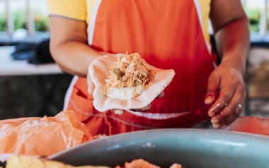 Elaboration of traditional pupusas, elaboration of the dough for traditional pupusas, Hands of saleswoman showing raw pupusa