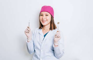 Diş aletleri tutan bir dişçi kadın portresi, izole arka planda ayna ve diş araştırması yapan dişçi kadın, diş aletleri tutan izole edilmiş genç dişçi.