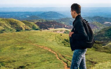 Yukarıdan tepeye bakan maceraperest bir adamın portresi. Sırt çantası uzaktaki bir tepeye bakıyor.