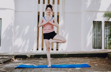Yoga vrikshasana ya da ağaç pozu veren bir kız. Vrikshasana yoga yapan genç bir kadın. Rahatlama ve yaşam enerjisi yoga konsepti