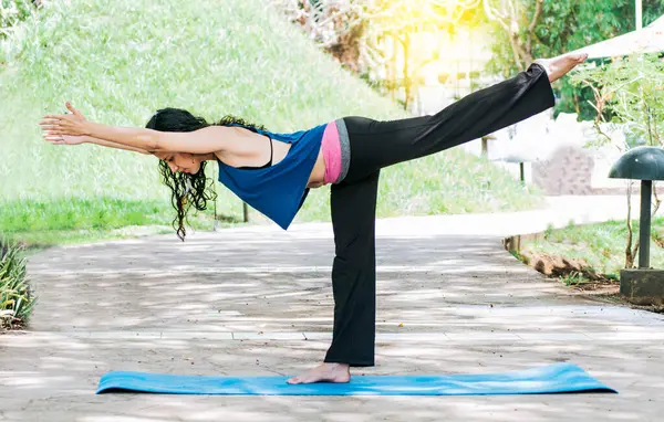 Stock image Woman doing warrior III yoga outdoors, girl doing Virabhadrana III yoga, young woman doing yoga outdoors, warrior III yoga concept