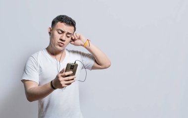 Handsome man listening to music with his cell phone with headphones isolated, people enjoying music with headphones isolated, cheerful guy listening to music with his cell phone isolated