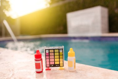 Water test kit for swimming pools, Chlorine and ph tester for swimming pools. Chlorine test kit on the edge of the pool,  Mini tester for pool maintenance clipart