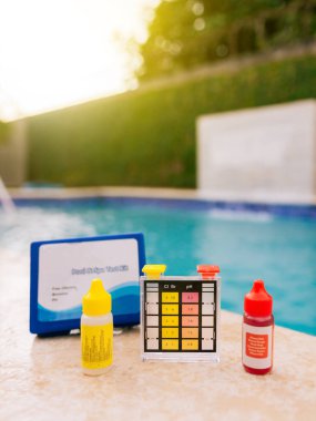 Havuz bakımı için pH testi. Yüzme havuzları için su test kiti, yüzme havuzları için klor ve ph testi. Klor test kiti havuzun kenarında.