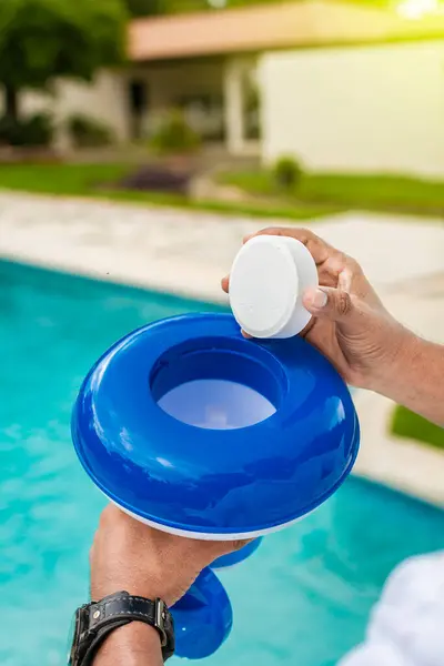 Stock image Hand of a pool disinfection worker holding a dispenser with a chlorine tablet. Hands holding a dispenser with pool chlorine tablet, pool float and chlorine tablets for pool maintenance. Hands holding a pool chlorine dispenser.