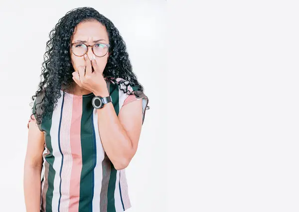 stock image Disgusted young afro woman covering nose. Woman in glasses covering nose from a bad smell isolated. Displeased afro girl holding her nose isolated