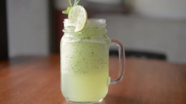 Tahta masadaki limonatayı tazeliyorum. Ahşap masadan buz gibi bir limonata alan kişi.