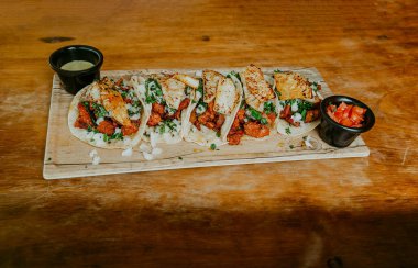 Ahşap arka planda servis edilen soslu Meksika tacosu al pastor.