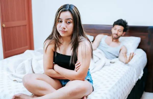 stock image Wife arguing with her husband in bed. Young couple arguing sitting on the bed. Concept of couple problems in bed. Upset woman with husband sitting on bed