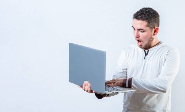 Laptop kullanan yakışıklı adam izole edilmiş. Elinde tuttuğu ve dizüstü bilgisayardaki terfiye bakan şaşırmış adam.