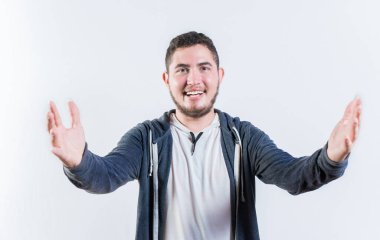 Dostça karşılayan genç bir adam, kolları açık, izole bir şekilde. Kameraya kollarını açan misafirperver adam.