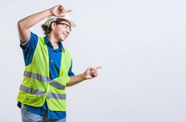 Gülümseyen Latin mühendis iki parmağı da izole bir şekilde kenarı işaret ediyor. İlan veren mutlu bir erkek müteahhit.