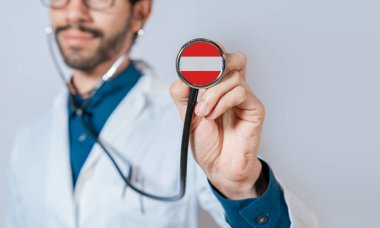 Avusturya bayrağıyla steteskop tutan doktor. Avusturya Sağlık ve Bakım Konsepti, steteskopta Avusturya bayrağı