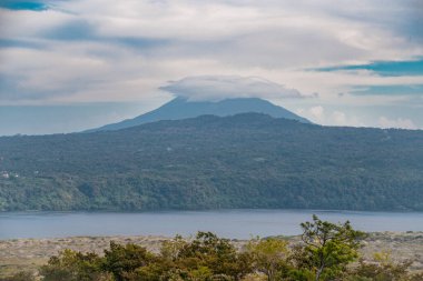 Yeşil bitki örtüsüyle çevrili mavi gökyüzü olan bir volkan, Nikaragua. Güneşli bir günde çevresi bitki örtüsüyle çevrili güzel bir volkan manzarası.