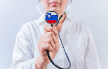 Slovenya bayrağıyla steteskop tutan kadın doktor. Slovenya 'nın ulusal sağlık sistemi