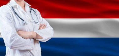 Hollanda bayrağında çapraz kollu bir doktor. Hollanda sağlık ve bakım konsepti. Hollanda bayrağında kadın doktor