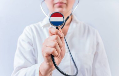 Hollanda bayrağıyla steteskop tutan kadın doktor. Hollanda 'nın ulusal sağlık sistemi