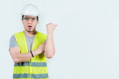 Şaşırmış Latin mühendis yan reklam alanı gösterdi. Şaşırmış erkek mühendis, tecrit edilmiş arka planda bir terfiye işaret ediyor.