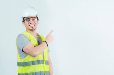 Yandan izole edilmiş mutlu erkek müteahhit. Gülümseyen erkek inşaat işçisi boşluğu işaret ediyor