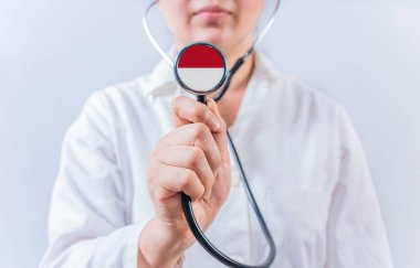 Kadın doktor elinde steteskopla Monako bayrağını tutuyor. Monako 'nun Ulusal Sağlık Sistemi