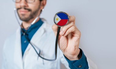 Filipin bayrağıyla steteskop tutan bir doktor. Filipinler Sağlık ve Bakım Konsepti, Filipinler steteskopunda bayrak