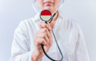 Endonezya bayrağıyla steteskop tutan kadın doktor. Endonezya 'nın ulusal sağlık sistemi