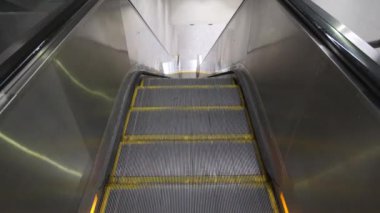 Bir yeraltı yürüyen merdiveninin üst görüntüsü yükseliyor. Merdivenlerdeki sarı çizgiler. 