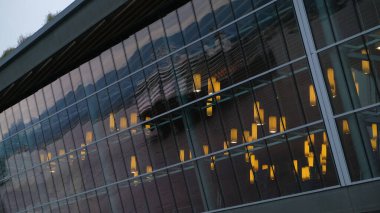 İçinde fenerler olan modern cam bina ve pencerelerinde büyük bir gemi ve dağların yansıması.. 