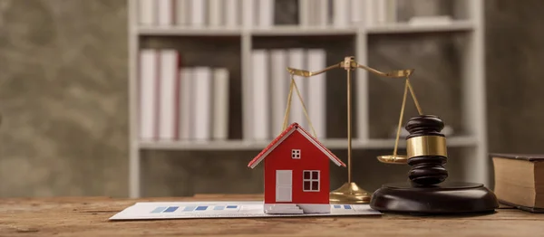 scales of justice, gavel and small wooden toy house, working with documents, signing contract agreements. Real estate law concept.