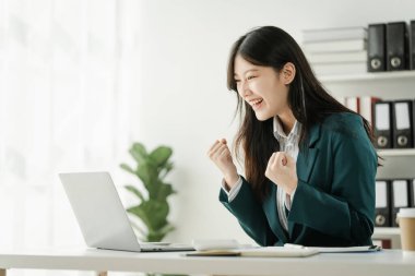 Finans kurumu çalışanı Asyalı kadınlar, görevlere dalmış profesyoneller. İş adamları özenle hesaplama yapar, müşterilere danışır ve masalarından anlaşma sağlarlar..