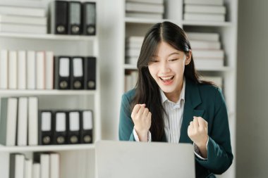 Finans kurumu çalışanı Asyalı kadınlar, görevlere dalmış profesyoneller. İş adamları özenle hesaplama yapar, müşterilere danışır ve masalarından anlaşma sağlarlar..