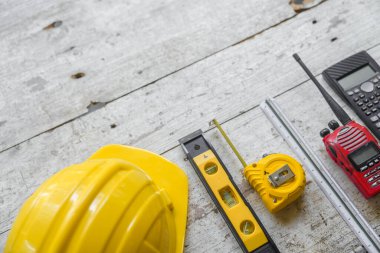 Sarı başlık, ruh seviyesi, mezura, ahşap zemin üzerine dizilmiş katlama cetvel gibi üst görünüm inşaat araçları.