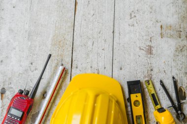 Sarı başlık, ruh seviyesi, mezura, ahşap zemin üzerine dizilmiş katlama cetvel gibi üst görünüm inşaat araçları.