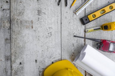 Sarı başlık, ruh seviyesi, mezura, ahşap zemin üzerine dizilmiş katlama cetvel gibi üst görünüm inşaat araçları.