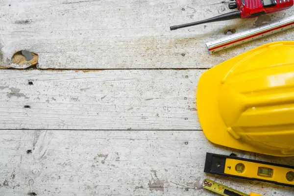 Sarı başlık, ruh seviyesi, mezura, ahşap zemin üzerine dizilmiş katlama cetvel gibi üst görünüm inşaat araçları.